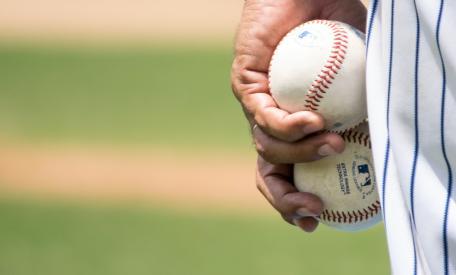 Een pitcher met twee honkballen in zijn hand.