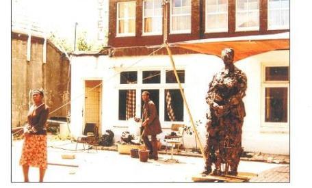 Nelson Carrilho werkend aan het beeld Mama Baranka in zijn tijdelijke studio in de Valkenburgerstraat, zomer 1984. Zijn moeder staat model. Foto: collectie Nelson Carrilho